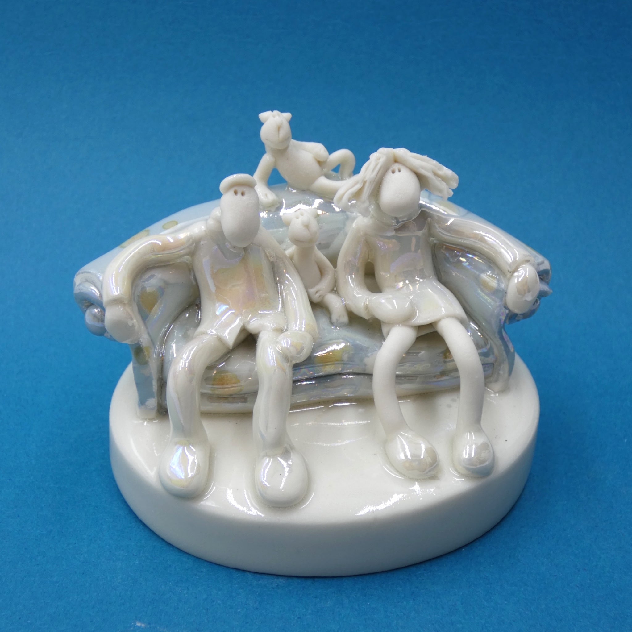 Porcelain sculpture of couple and cats on sofa by artist Andrew Bull