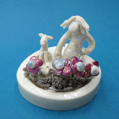 Porcelain sculpture of a lady planting flowers and a dog burying his bone by artist Andrew Bull