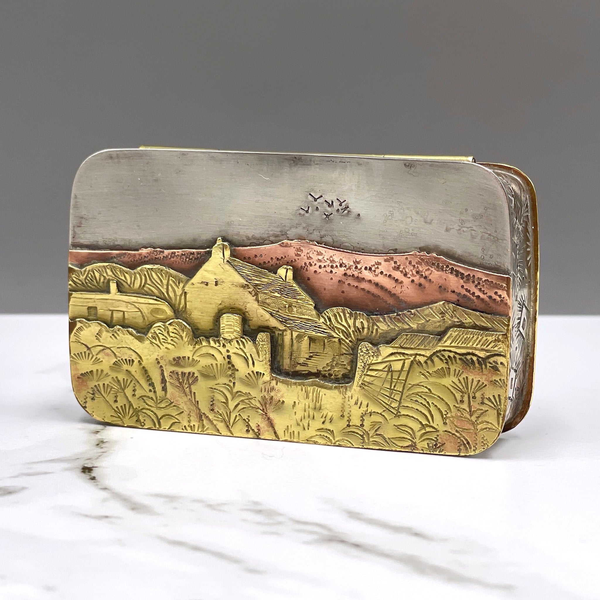 Metal hinged box depicting birds flying over a farmhouse in the heat of the summer by artist Cornelius Van Dop
