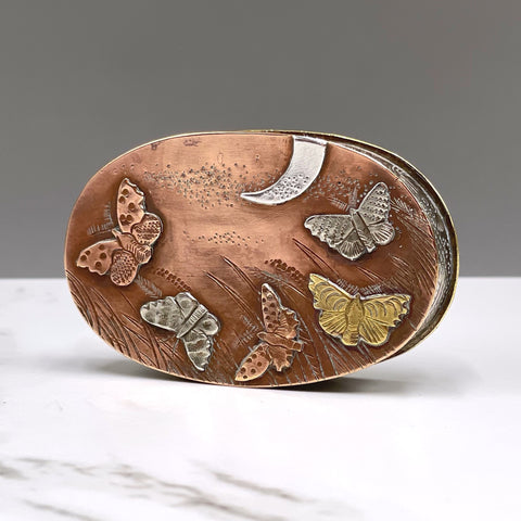 Metal box depicting moths flying in the moonlight by artist Cornelius Van Dop