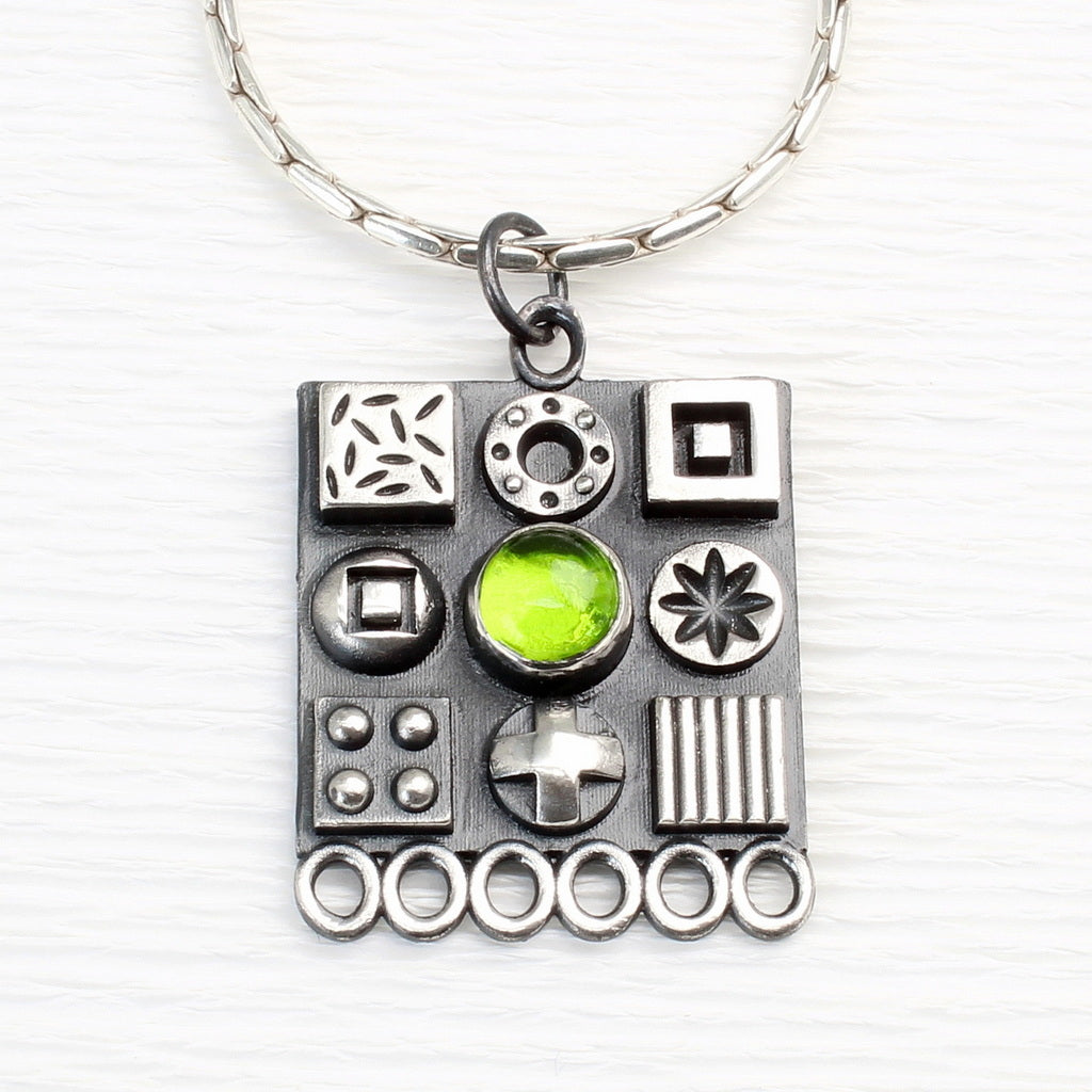 Square sterling silver pendant with 3D symbols and a peridot gemstone by jewellers John and Dawn Field 