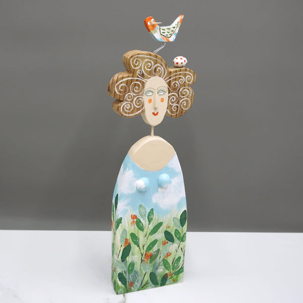 Driftwood sculpture of a bird laying an egg and making a nest in a lady's hair by artist Lynn Muir