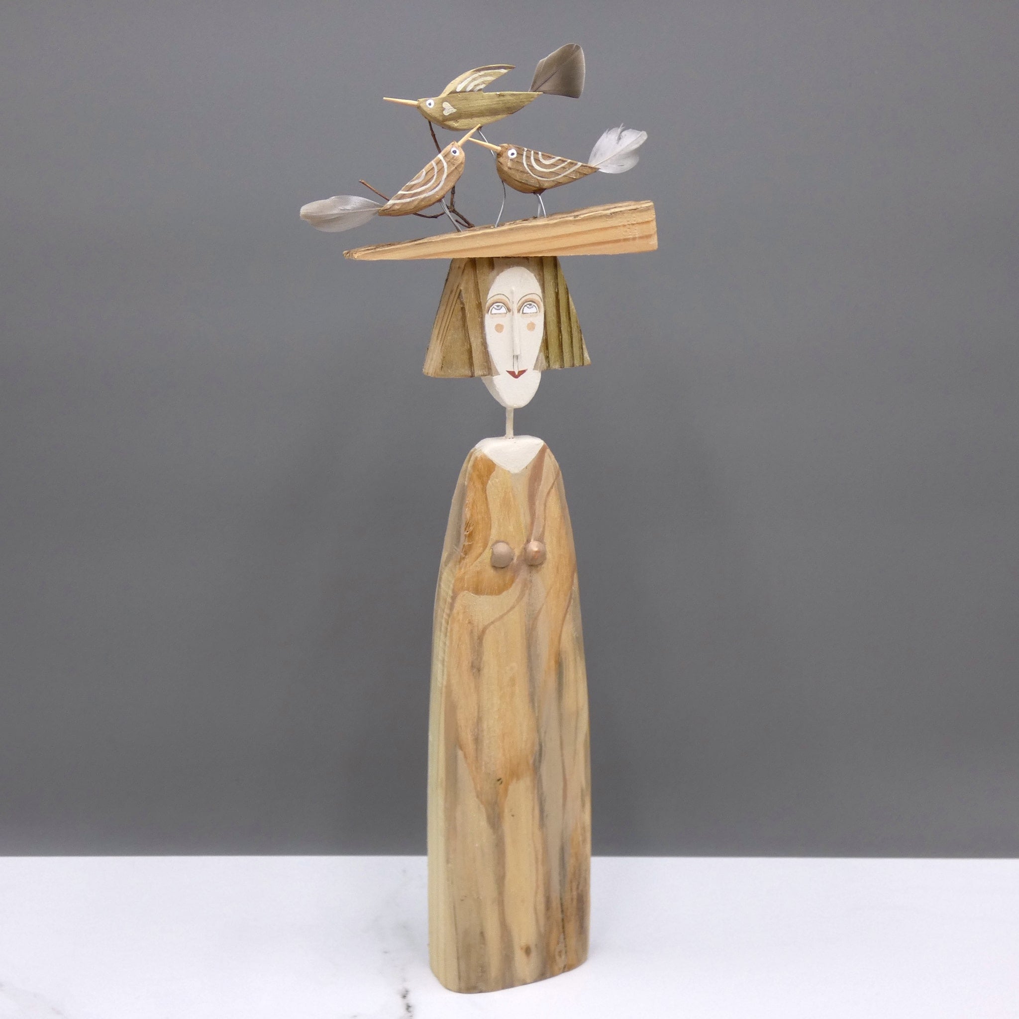 Driftwood sculpture of three birds sitting on a lady's hat by artist Lynn Muir.