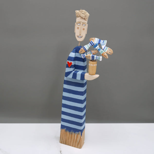 Driftwood sculpture of a man carrying a decorative fish pot by artist Lynn Muir