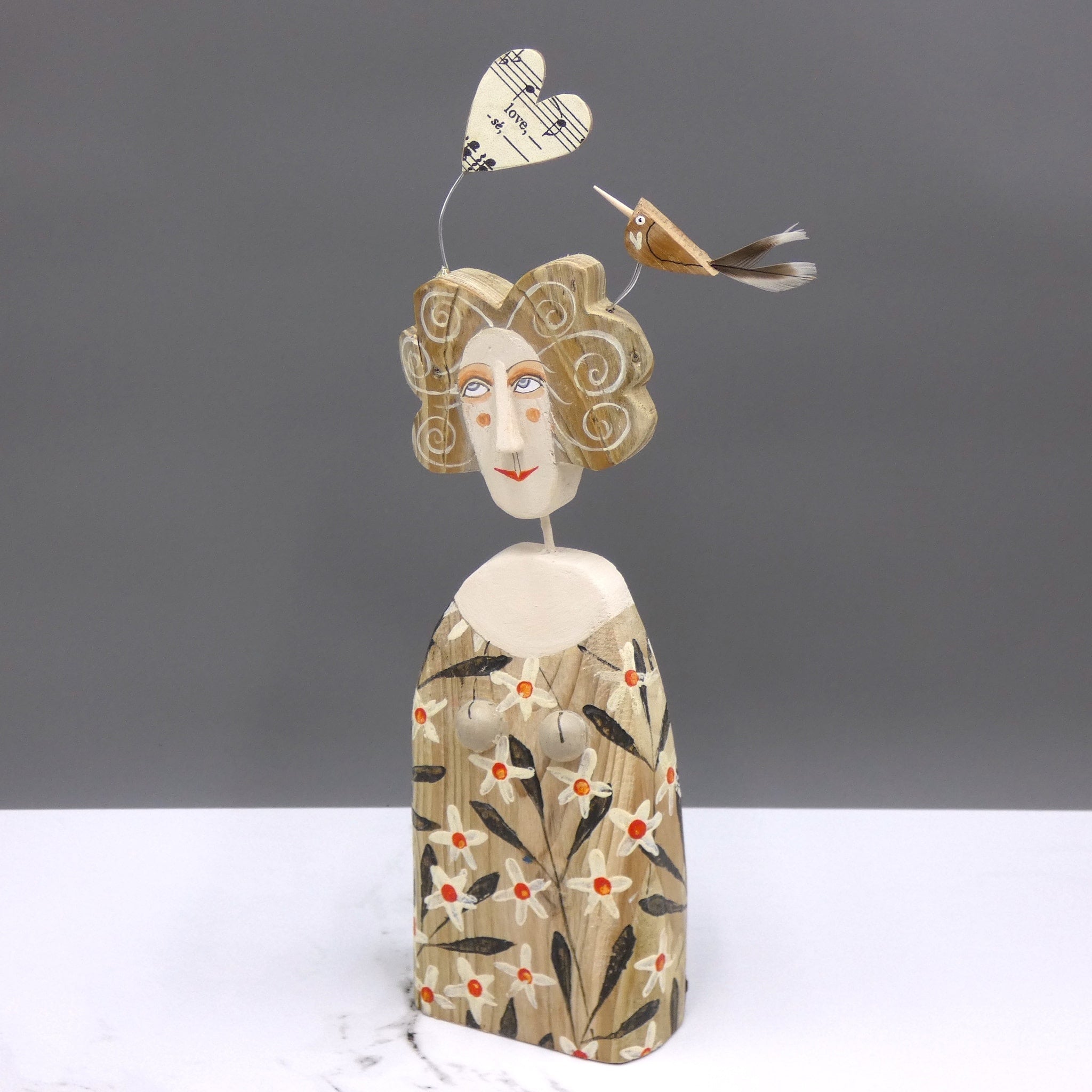 Driftwood sculpture of a bird sitting on a lady's hair by artist Lynn Muir.