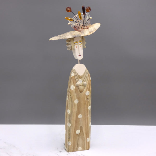 Driftwood sculpture of a lady wearing a polka dot dress and a fancy hat by artist Lynn Muir