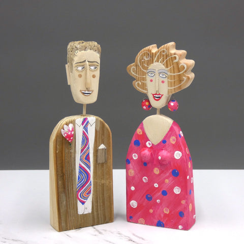 Driftwood sculptures of man wearing a suit with a colourful tie and a woman wearing a polka dot dress with matching earrings by artist Lynn Muir
