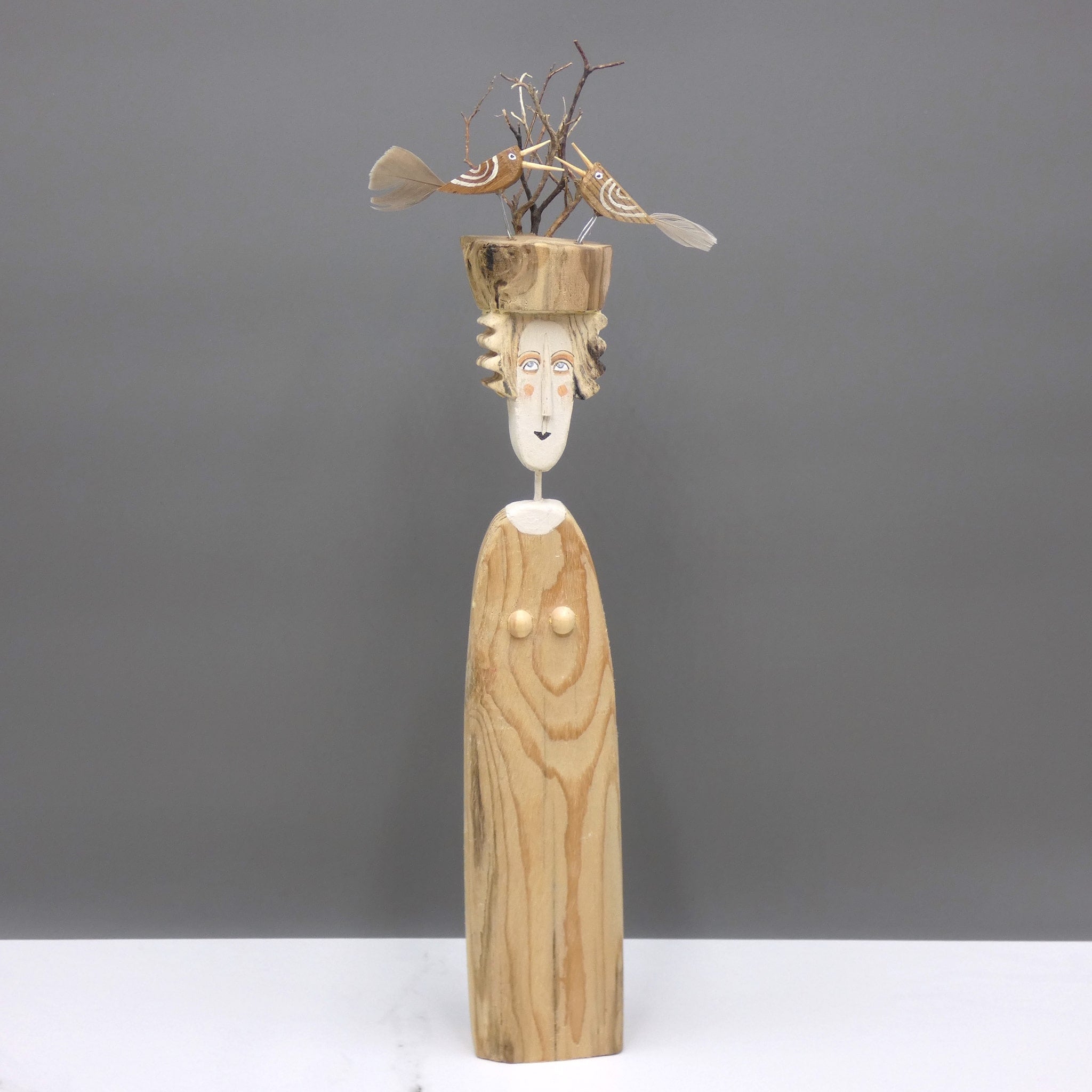 Driftwood sculpture of a woman with two birds on her hat by artist Lynn Muir