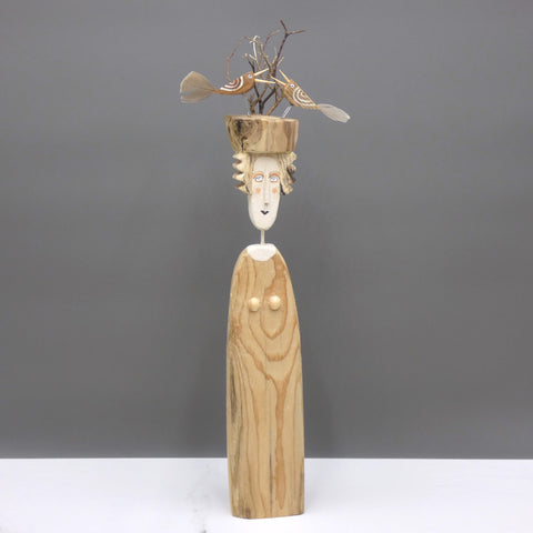 Driftwood sculpture of a woman with two birds on her hat by artist Lynn Muir