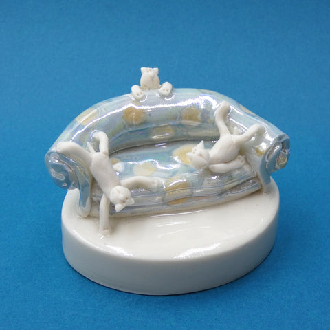 Porcelain sculpture of three cats playing on the sofa by artist Andrew Bull