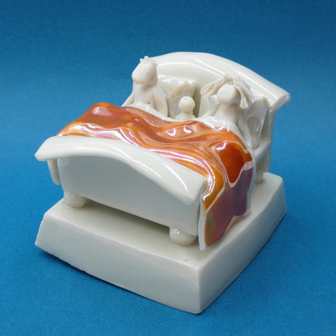 Porcelain sculpture of couple and baby in bed by artist Andrew Bull