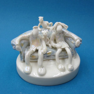 Porcelain sculpture of couple and cats on sofa by artist Andrew Bull