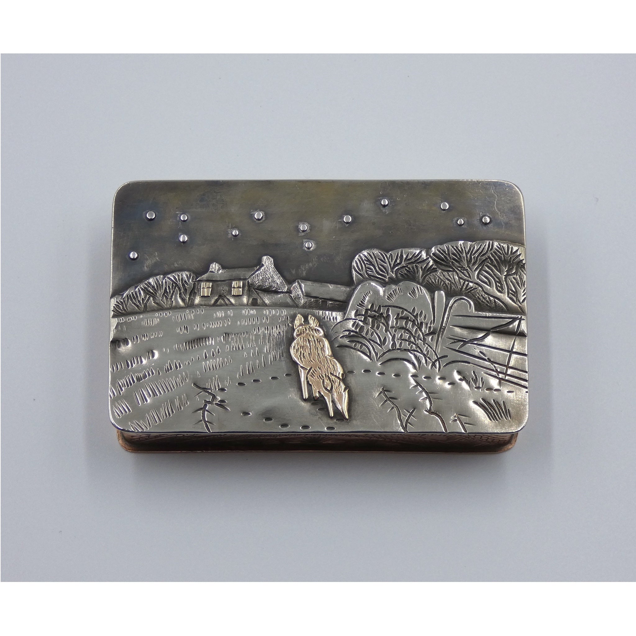 Metal hinged box depicting a fox walking through a snow covered field towards a cottage in the dead of night by artist Cornelius Van Dop